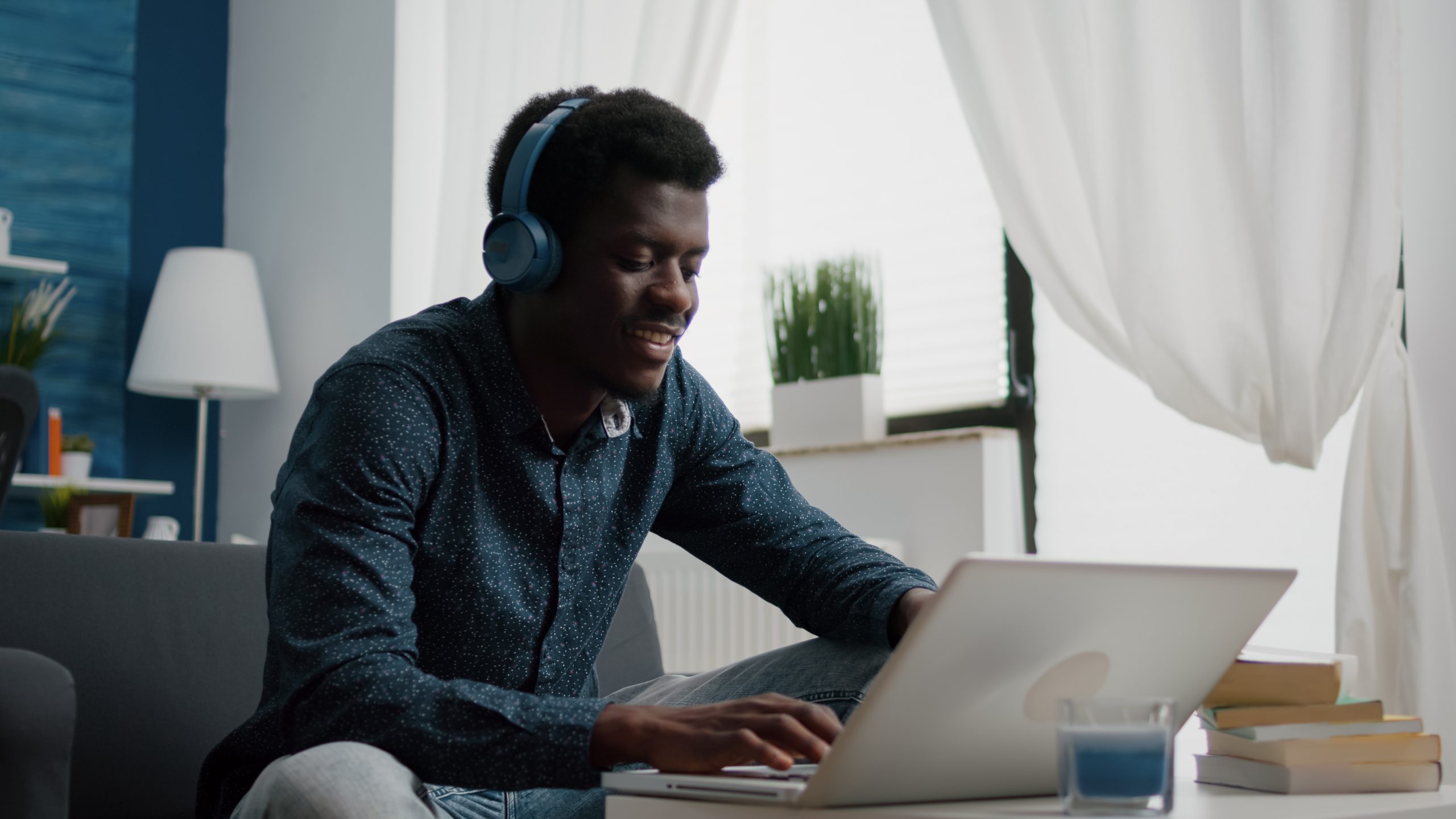 You man wearing heaphones and typing at laptop.